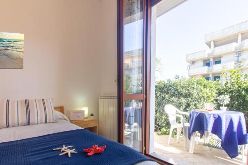 马帝斯兹罗Appartamento La Pineta Nord - MyHo Casa的一间卧室配有一张床、一张桌子和一个窗户。
