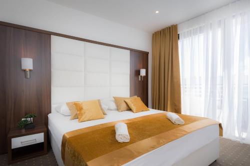 罗戈兹尼察Hotel Perla的一间卧室配有一张大床和两条毛巾