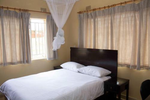 利隆圭Chrinas Guest House的一间卧室配有一张带白色床单的床和一扇窗户。