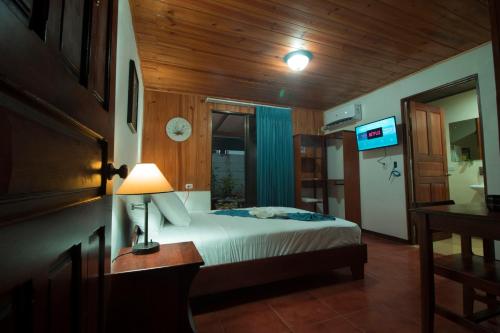萨拉皮基Tirimbina Rainforest Lodge的一间卧室配有一张床和一张带台灯的桌子