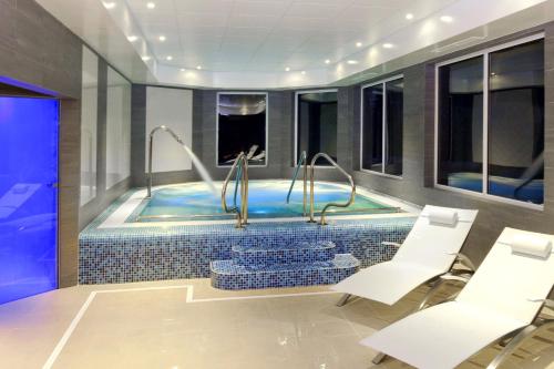 AlbourneWickwoods Country Club Hotel & Spa的一个带白色椅子和桌子的房间的游泳池