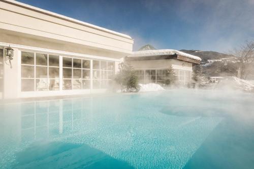 齐勒河谷采尔特里萨健康-美食-酒店的大楼前的大型游泳池