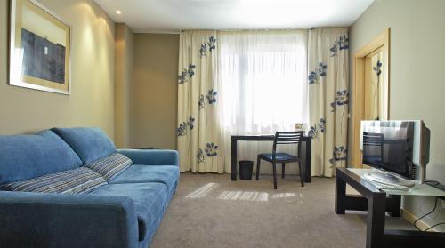 伊马科茵Blu Hotel Pamplona的客厅配有蓝色的沙发和电视