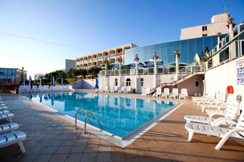 波雷奇Hotel Istra Plava Laguna的一座带白色椅子的游泳池和一座建筑