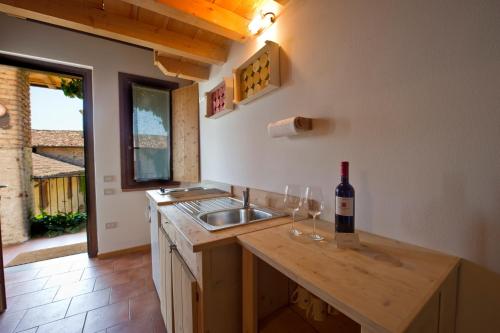 代森扎诺-德尔加达波勾三多尼诺酒店的厨房配有水槽,柜台上提供一瓶葡萄酒