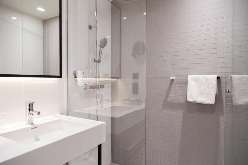 赫尔辛基Holiday Inn Helsinki - Expo, an IHG Hotel的白色的浴室设有水槽和淋浴。