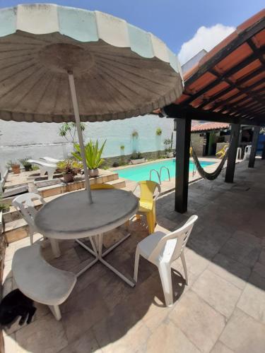 卡波布里奥Rock n Hostel的游泳池旁遮阳伞下的桌椅