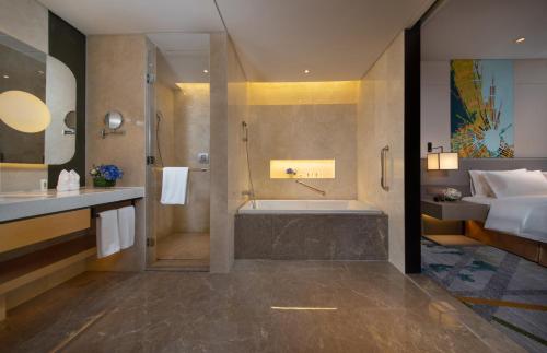 萧山杭州空港假日酒店的一间带浴缸和淋浴的浴室以及一张床