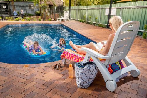 阿德莱德Adelaide Caravan Park - Aspen Holiday Parks的一名女子和两名儿童在游泳池玩耍