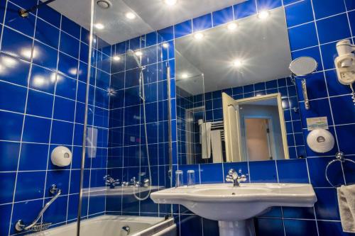 金沙丽利亚酒店的蓝色瓷砖浴室设有水槽和浴缸