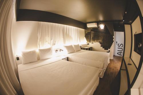 马塞约Wanderlust Hostel的小客房内的两张床,配有白色床单