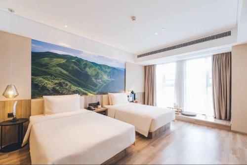 临沂市Atour Hotel Linyi High Speed Railway Station Yimeng North Road的两张位于酒店客房的床,墙上挂着一幅画