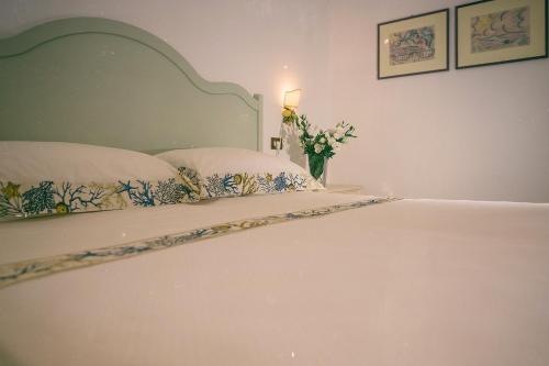 伊斯基亚Hotel Villa Maria的一张带两个枕头的白色床和花瓶