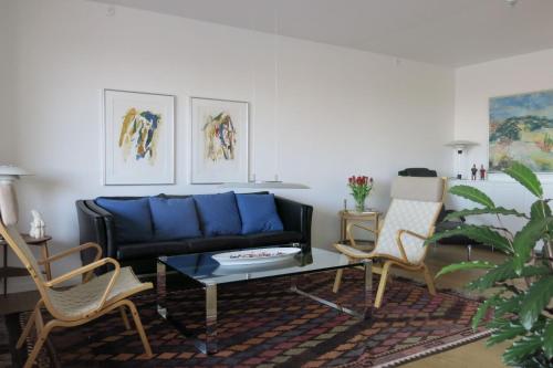 哥本哈根ApartmentInCopenhagen Apartment 1442的客厅配有蓝色的沙发和两把椅子