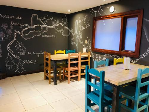 圣卡洛斯-德巴里洛切Hostel Olimpo House的用餐室设有粉笔板墙,配有桌椅