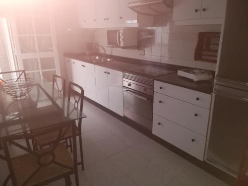 格罗韦Piso de Verano的厨房配有白色橱柜和桌椅
