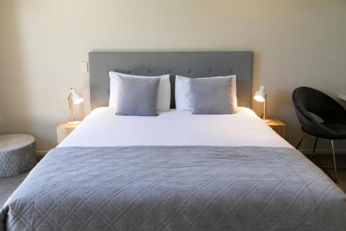 陶波Alpine Lake Motel的卧室配有一张带白色床单和枕头的大床。