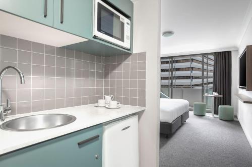 悉尼曼特拉查特斯伍德酒店的一间带水槽的浴室和一张位于客房内的床