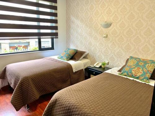 昆卡HOSTAL EL CAJAS的酒店客房设有两张床和窗户。