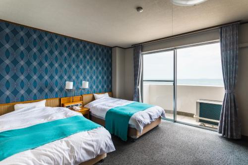 EtajimaUminos Spa & Resort的酒店客房设有两张床和大窗户。