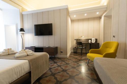 卡塔尼亚B&B Palazzo Perrotta的酒店客房配有两张床、一把椅子和一张书桌