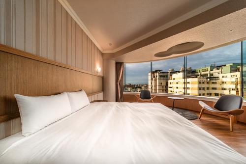 屏东县鮪魚家族飯店-屏東館的卧室设有一张白色大床和一扇窗户。