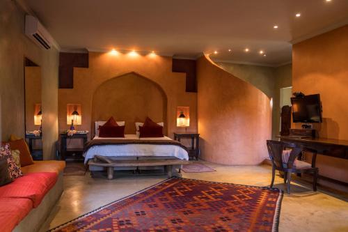 伊丽莎白港Singa Lodge - Lion Roars Hotels & Lodges的一间卧室配有一张床和一个沙发