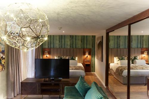 克鲁Wychwood Park Hotel and Golf Club的一间卧室配有两张床、一台电视和吊灯。