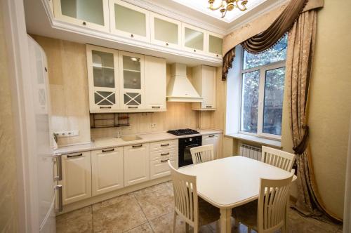 基辅Kyiv 2Rooms Classic Apartment的厨房配有白色橱柜、桌子和窗户。