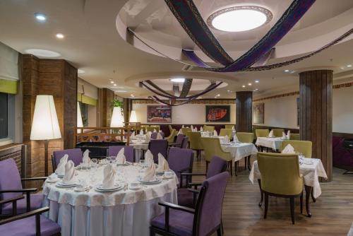 阿斯塔纳杜门酒店的一间设有白色桌子和紫色椅子的用餐室