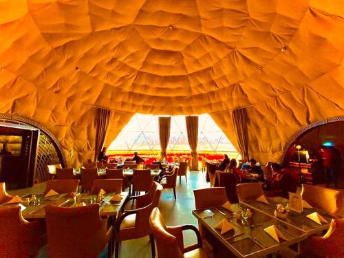 瓦迪拉姆Wadi Rum UFO Luxotel的餐厅拥有带桌椅的大型天花板。