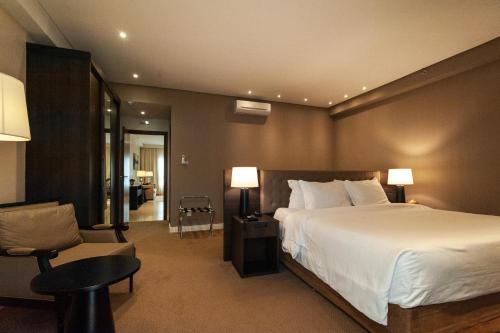 阿纳波利斯Radisson Hotel Anápolis的卧室配有一张白色大床和一把椅子