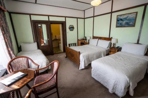 麦克鲁姆Coolcower House的酒店客房带两张床和一张桌子以及椅子。