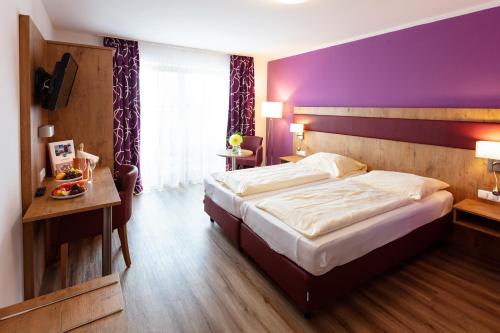 瓦勒湖畔诺伊马克特荷索度假酒店的一间卧室设有一张大床和紫色的墙壁