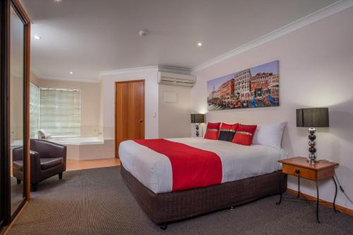 布里斯班阿斯普雷卡尔瑟尔汽车旅馆的一间卧室配有一张带红色毯子的大床