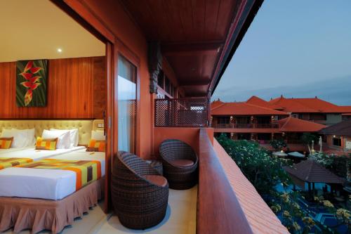 库塔库塔巴厘岛温纳别墅假日酒店的酒店客房设有带一张床和两把椅子的阳台