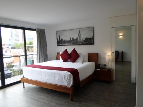 墨西哥城阿尔莫尼套房酒店的一间卧室设有一张大床和一个大窗户