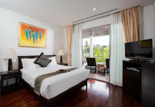 卡塔海滩Kata gardens 2 bedroom near Kata beach 3B的一间卧室配有一张床、一台电视和一个阳台
