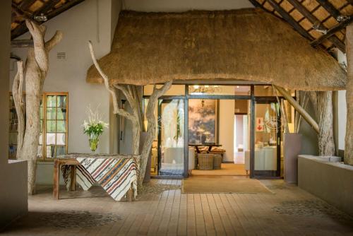 Karongwe Game ReserveKarongwe Portfolio- Shiduli Private Game Lodge的一座带茅草入口的建筑,配有桌子和树木