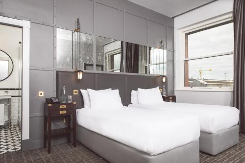 贝尔法斯特贝尔法斯特泰坦尼克酒店的卧室设有一张白色大床和一扇窗户。