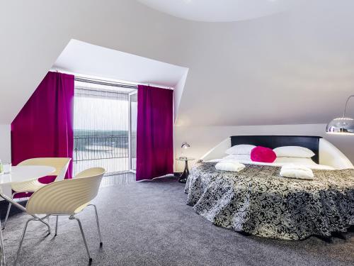 卢布涅维采沃茵斯基Spa酒店的一间卧室配有一张大床和一张桌子及椅子