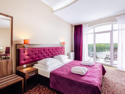 卢布涅维采沃茵斯基Spa酒店的一间卧室配有一张带紫色床罩的床和窗户。