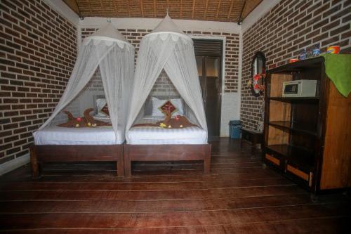 金巴兰Balangan海景简易别墅的砖墙间内的两张床和窗帘