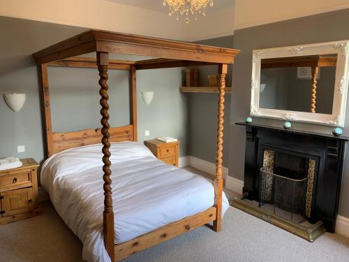 马基特德雷顿Lansdown House Bed & Breakfast的一间卧室设有一张天蓬床和一个壁炉