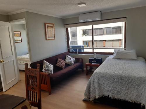 圣地亚哥Isabel Suites Vitacura的一间卧室配有一张床、一张沙发和一个窗口