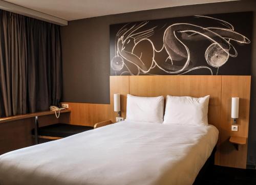 圣热尼普伊宜必思圣热尼普伊日内瓦酒店的酒店客房设有一张床,墙上挂有绘画作品