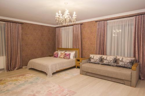 FedorovkaСтарий Тудорів的一间卧室配有一张床、一张沙发和一个吊灯。