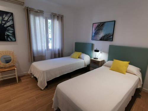 波连萨港Villa Bahía的配有白色和黄色枕头的客房内的两张床