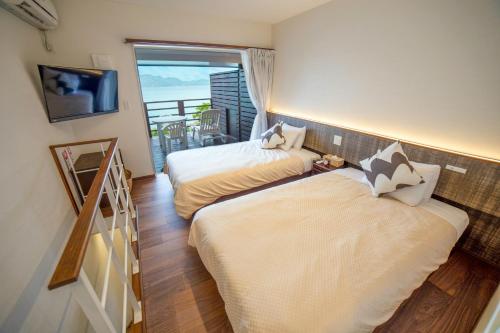 龙乡町美阿丹海滩酒店的带阳台的客房内的两张床