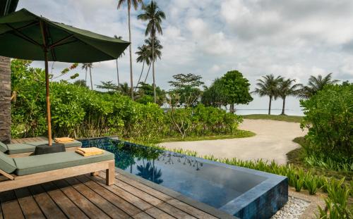 Kawal民丹岛别墅的一个带遮阳伞的庭院和一个海滩旁的游泳池